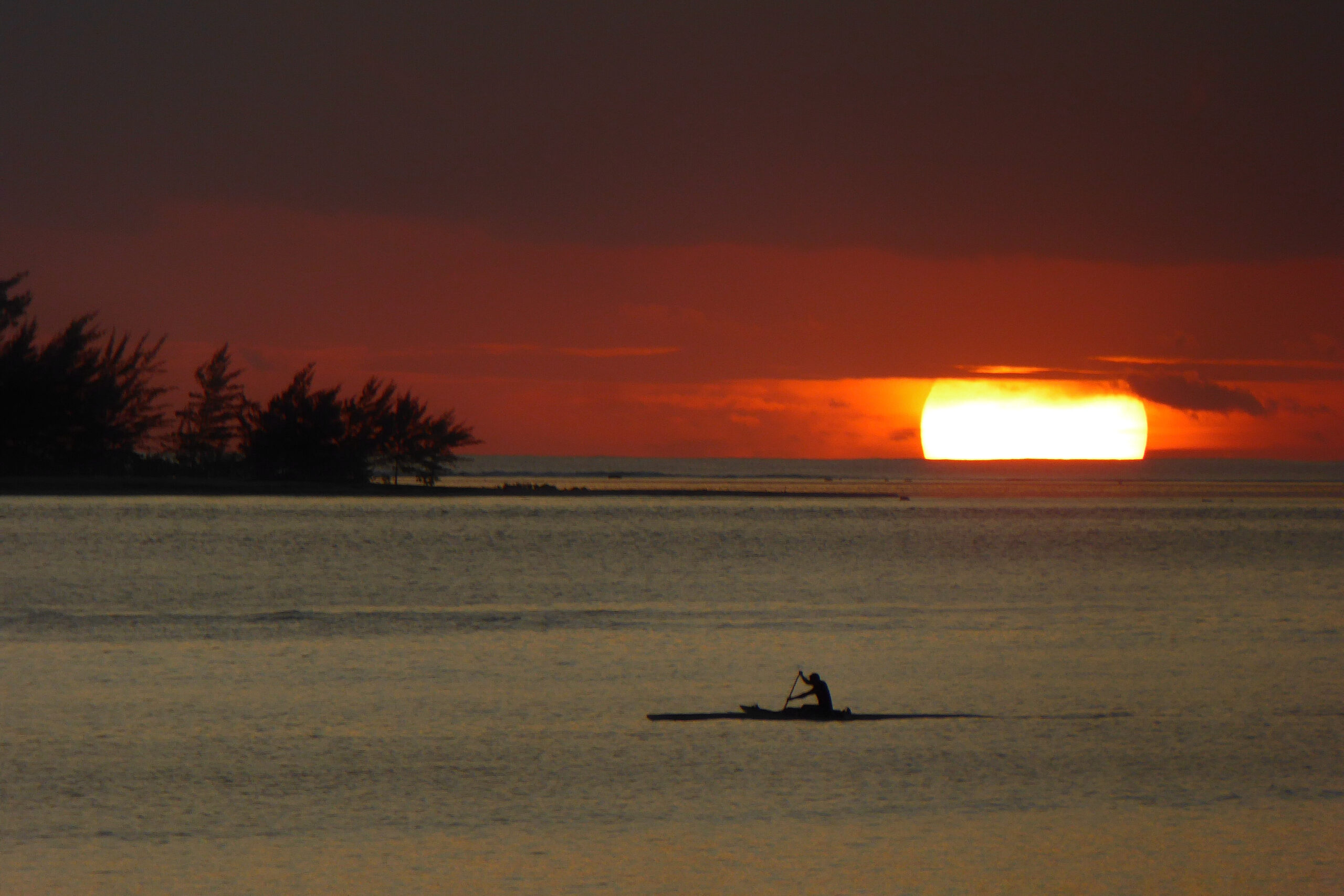 Coucher de soleil sur l'île de Bora Bora avec un Polynésien sur sa pirogue