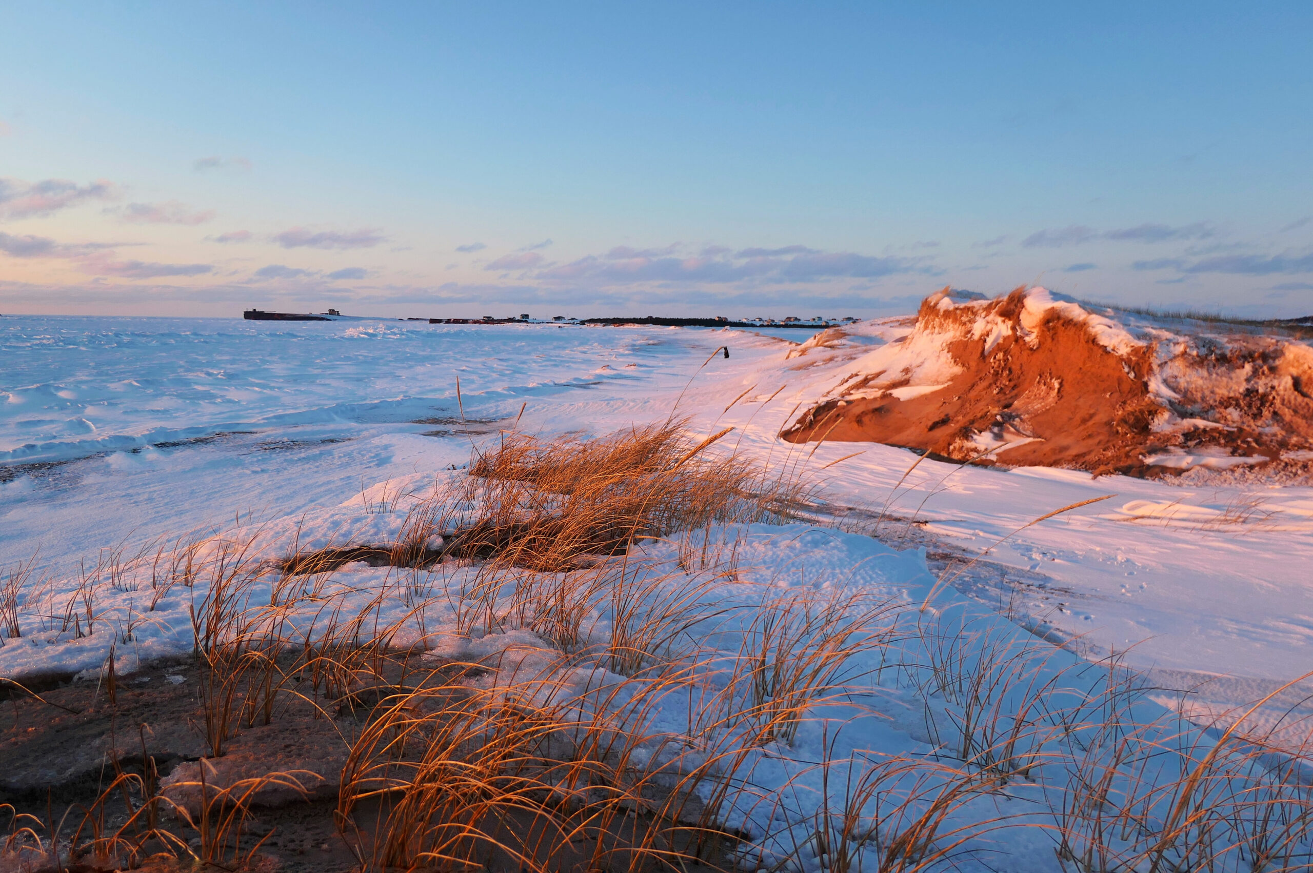 Coucher de soleil sur une plage enneigée et mer gelée, Îles de la Madeleine