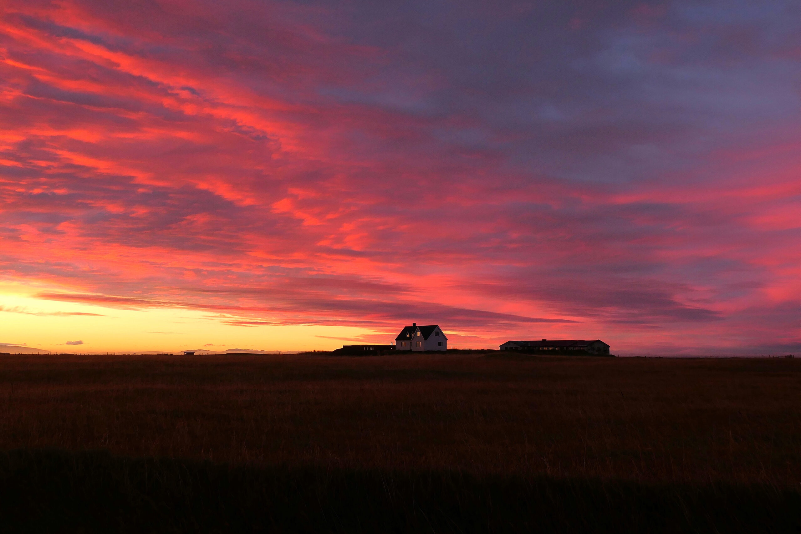 iel coloré par le coucher de soleil avec une maison au loin en Islande