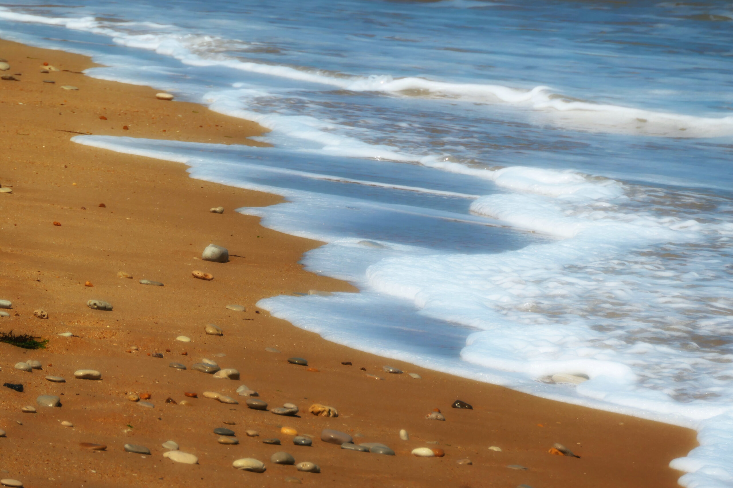 Gros plan d'une fin de vague s'écrasant doucement sur le sable.