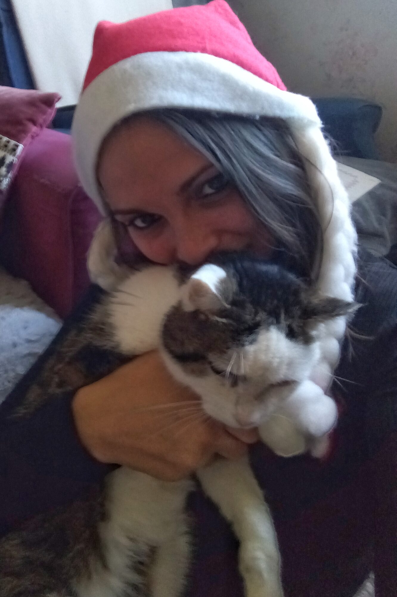 Femme portant un bonnet de Noël tenant et câlinant son chat