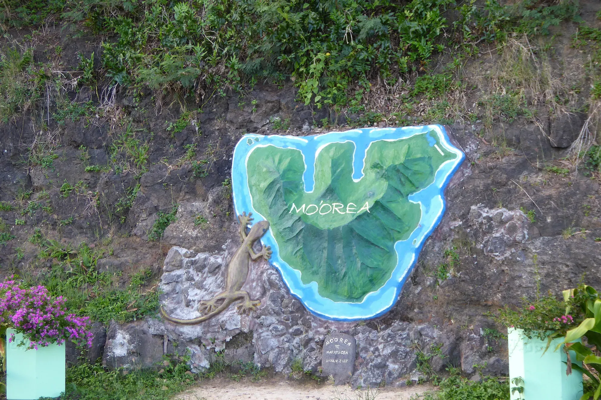 Fresque carte de Moorea et lézard sculpté — Polynésie française Fresque murale sur roche représentant la carte de l'île de Moorea avec un lézard sculpté, référence au nom tahitien Moʻoreʻa signifiant "lézard jaune", Polynésie française