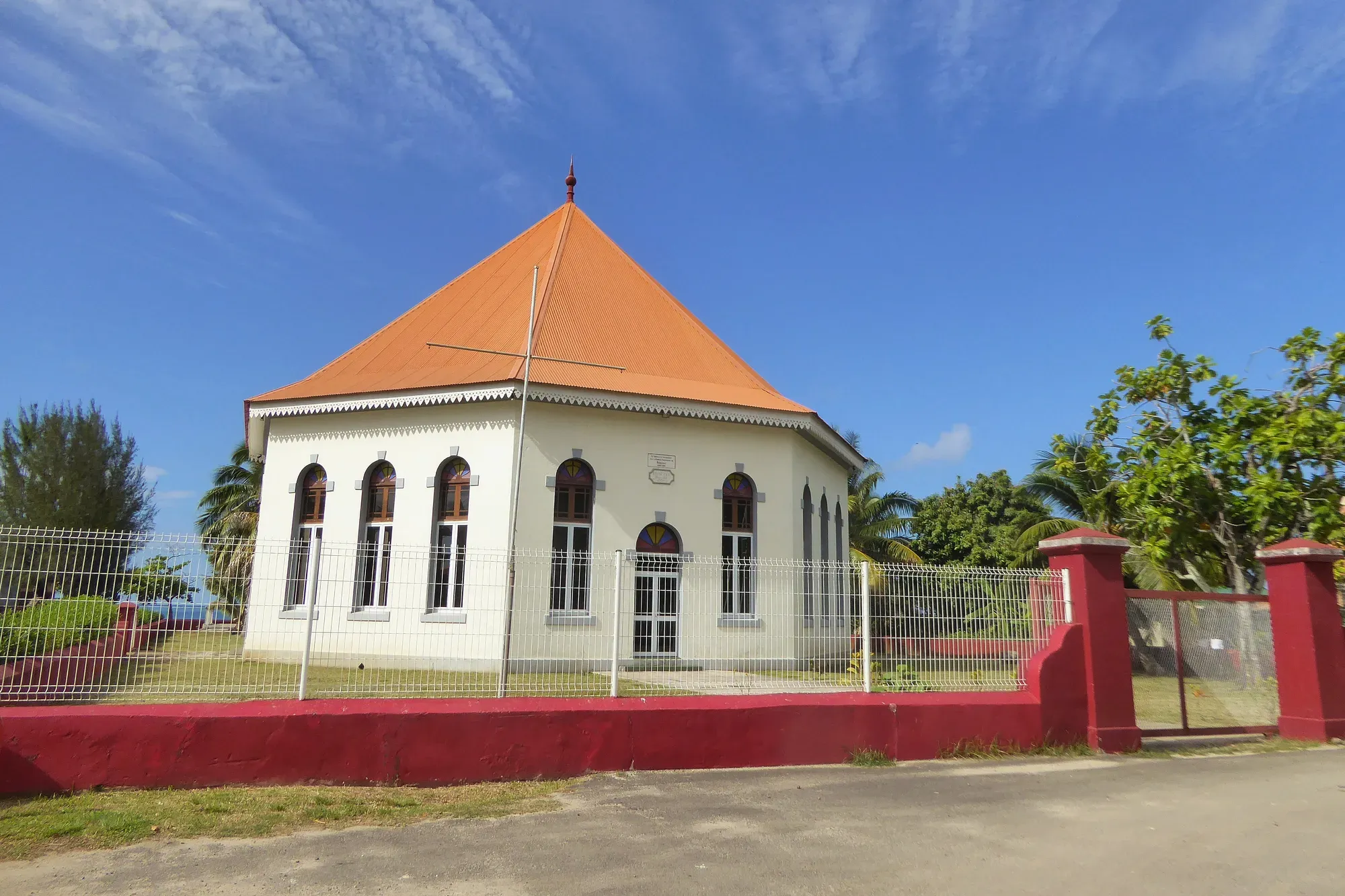 Église protestante avec toit orange octogonal et murs blancs entourée de végétation tropicale, Moorea, Polynésie française