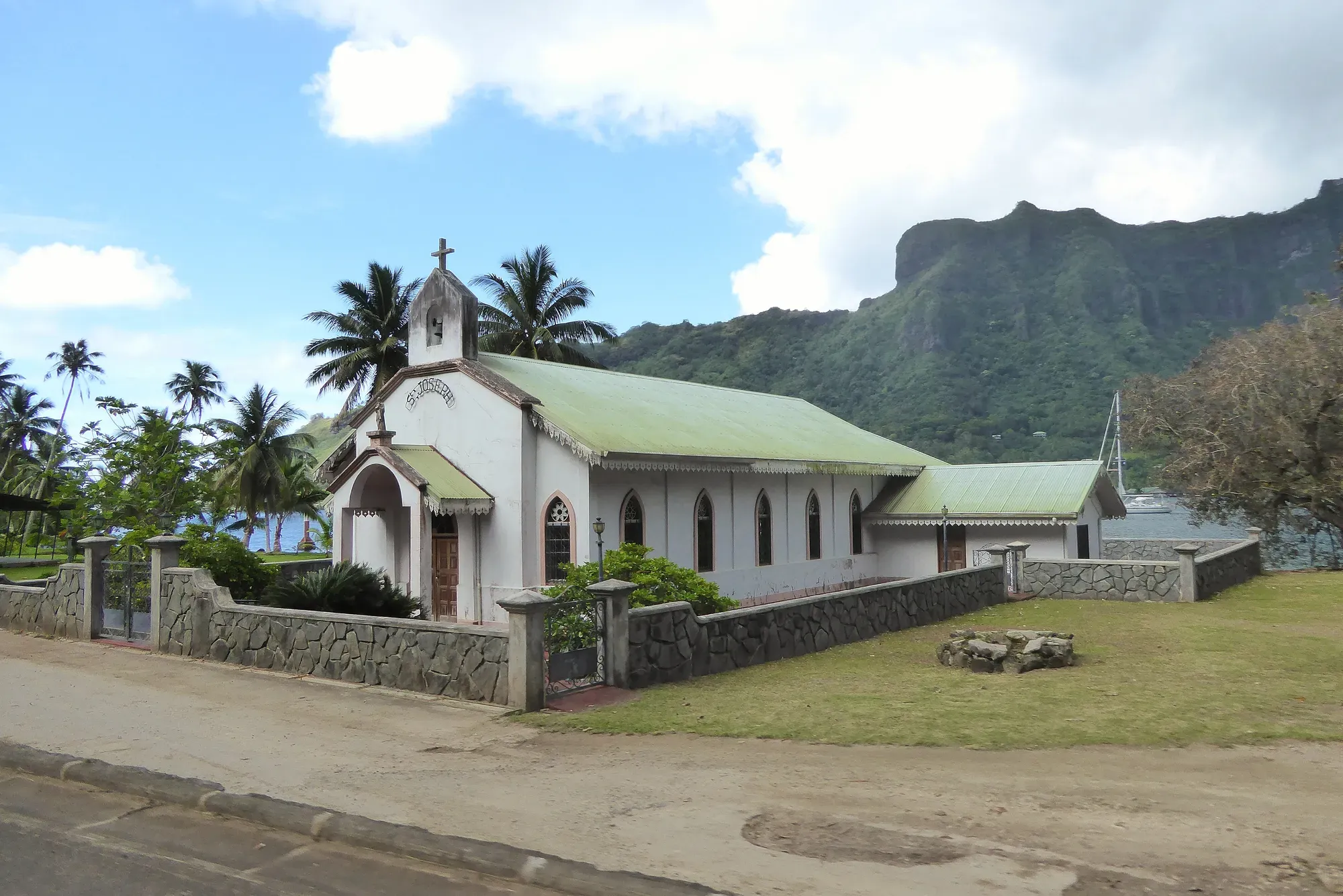 Église Saint-Joseph au toit vert et murs blancs avec une montagne volcanique verdoyante en arrière-plan, Moorea, Polynésie française