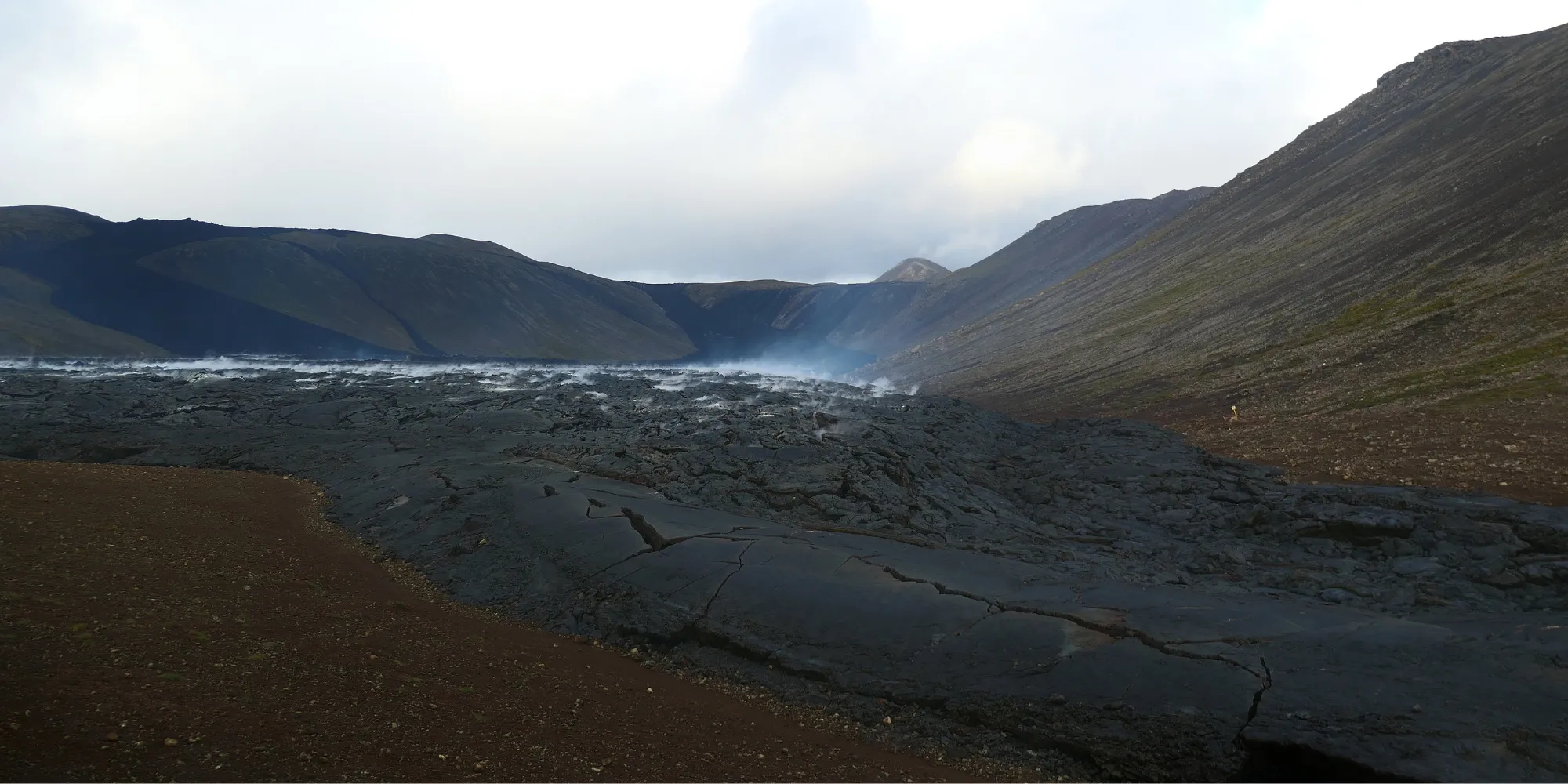 Coulée de lave noire envahissant une vallée islandaise Coulée lave noire fumante vallée Islande