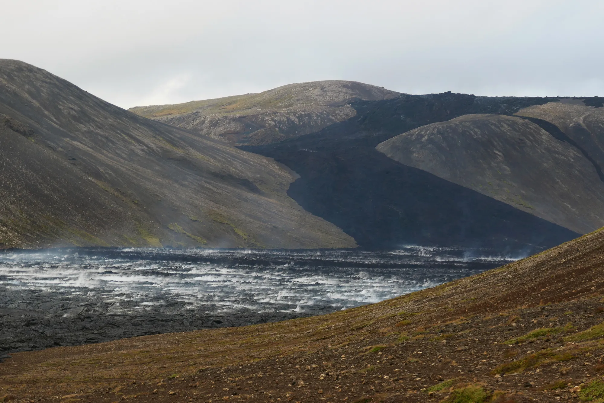 Rivière de lave figée entre les montagnes d'Islande Rivière lave figée montagnes vapeur Islande